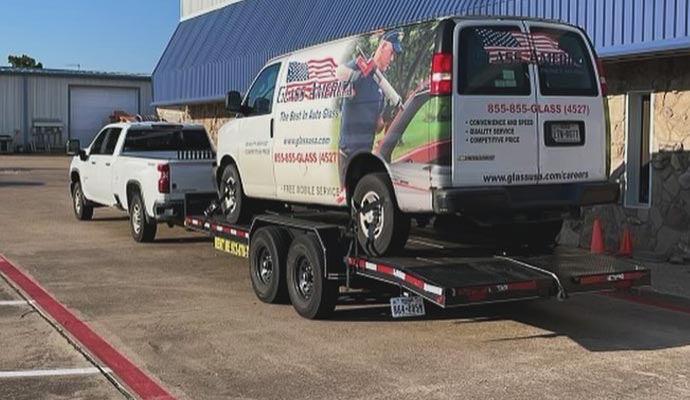 Pickup truck towing a trailer with a business service van loaded on it