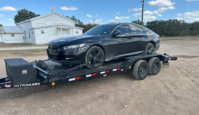 A wide, low-clearance car loaded on a 102-inch PJ SuperWide trailer with drive-over fenders for easy loading.