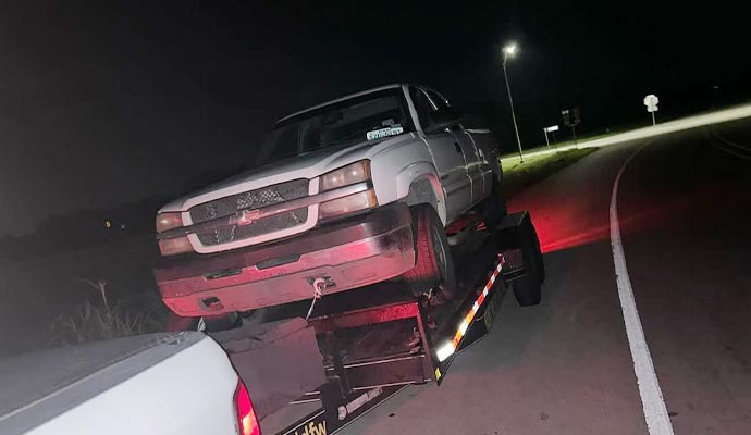Car being hauled on a trailer on the road at night