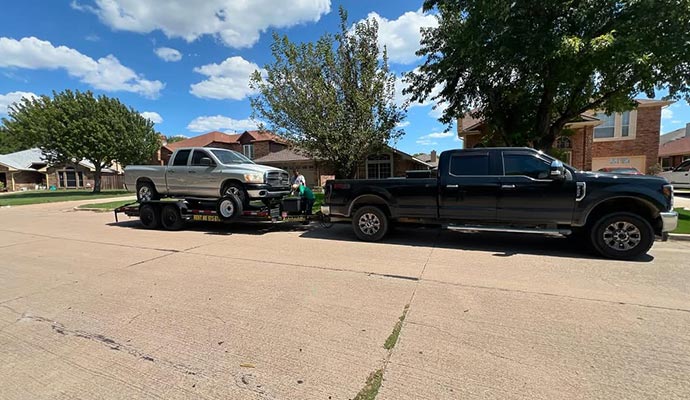 Loading a car onto a trailer being hauled by a black pickup truck