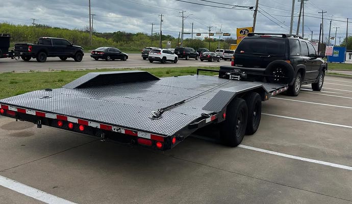 A flatbed car hauler trailer attached to an SUV, illustrating how to choose the right trailer based on hauling needs.