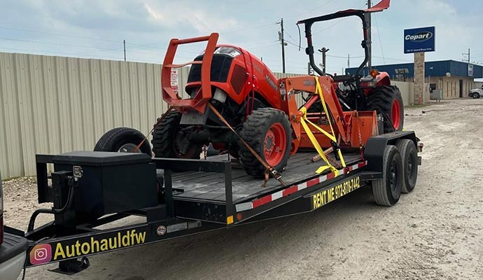 Farm equipment securely loaded on a flatbed trailer for transport between agricultural properties.