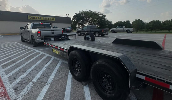 Big Tex trailer being towed by a pickup truck in a parking lot