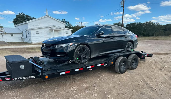 Black Honda Accord sedan loaded onto a flatbed trailer for transport