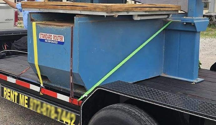 Heavy machinery securely strapped on a flatbed trailer for safe transport to a construction or job site.