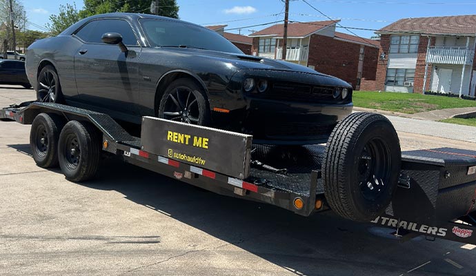 A black race car secured on a flatbed trailer, demonstrating safe and controlled transport for racing vehicles.